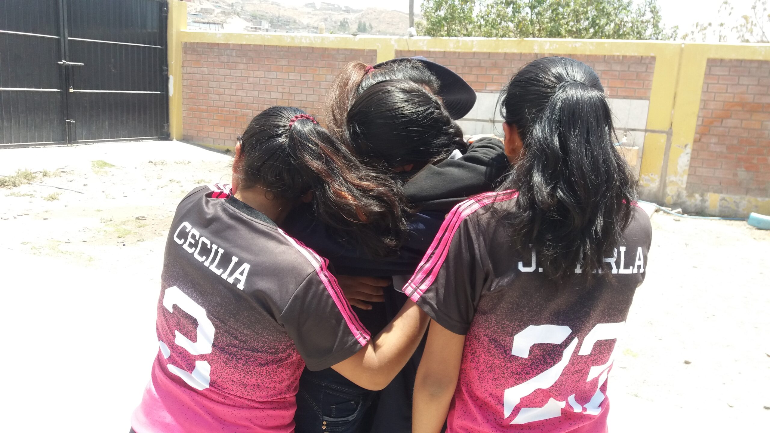 Girls in team jerseys in a huddle at the home